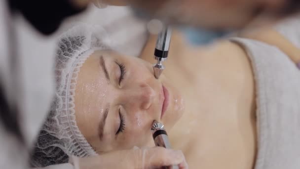 美容师医生让女人面对小电流疗法 女孩皮肤护理在温泉诊所抗老化 美容师利用电脉冲进行面部美容治疗 纵向观点 — 图库视频影像