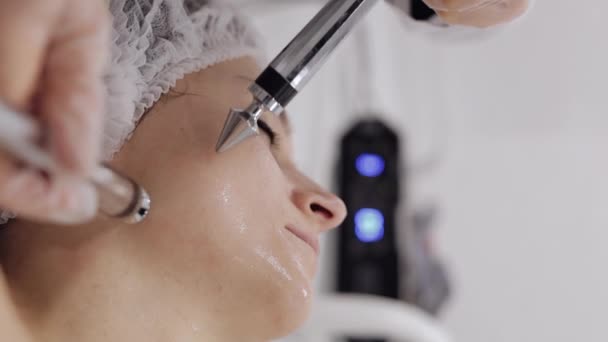 美容师让女人面对小电流疗法 女孩皮肤护理在温泉诊所抗老化 美容师医生使用电脉冲进行面部美容治疗 纵向观点 — 图库视频影像