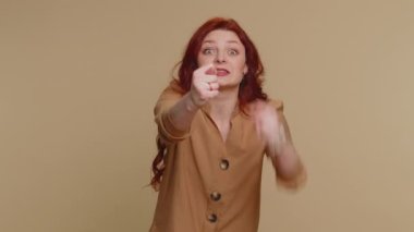 Angry aggressive redhead woman showing fig negative gesture, you dont get it anyway. Rapacious, avaricious, acquisitive. Body language. Refusal fig sign. Greedy avaricious girl on beige background