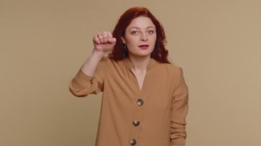 Knock-knock who is there. Confused redhead woman knocking door gesture asking who is at home, feeling embarrassed, no idea, being clueless and uncertain. Young ginger girl on beige studio background