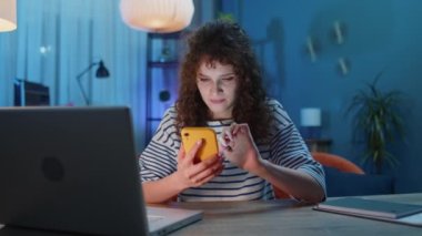 Displeased woman sitting at the office desk use laptop typing browsing working, loses becoming surprised sudden lottery results bad news, fortune loss fail. Adult girl at home in evening room on couch