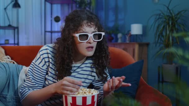 兴奋的女人躺在橙色沙发上吃爆米花零食 在家里看有趣的电视连续剧 体育比赛 在线社交媒体电影内容 享受夜晚娱乐的女孩 — 图库视频影像