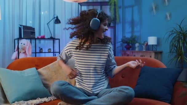 Kablosuz Kulaklıklarla Kıvırcık Saçlı Mutlu Rockçı Kadın Evde Dans Ediyor — Stok video