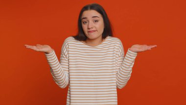 I dont know what to say. Confused woman feeling embarrassed about ambiguous question, having doubts, no idea, being clueless and uncertain. Young pretty girl isolated on red studio wall background