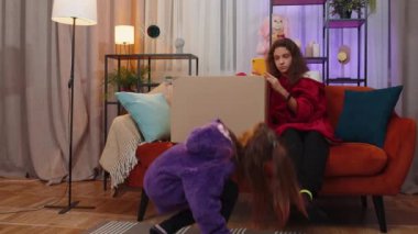 Little girls playing hide and seek, peekaboo game. Hiding inside cardboard box. Toddler child searching looking for sister, having no idea where is she. Three siblings children kids or friends at home