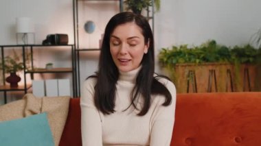 Oh my God, Wow. Surprised woman with brunette hair at home couch, shocked by sudden victory triumph, good win news, celebrating lottery jackpot luck. Excited amazed girl in living room apartment