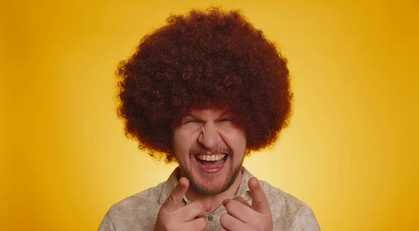 Joyful man with lush Afro hairstyle coiffure laughing out loud after hearing ridiculous anecdote, funny joke, feeling carefree amused, positive people lifestyle. Young hipster guy on yellow background