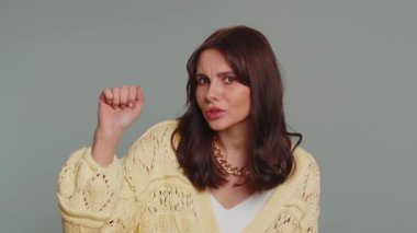 Knock-knock who is there, anybody home. Confused pretty woman knocking door gesture asking who is at home, feeling embarrassed, no idea, being clueless and uncertain. Young girl on gray background