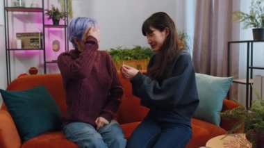 Two lesbian women family couple. Homosexual female girl gay making a surprise engagement ring love proposal of marriage to her beloved woman. Accepting emotionally say yes. LGBT people at home room