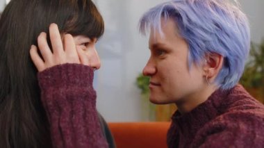 Close-up portrait of two young lesbian women family couple. Girls embrace hug each other at home indoor. LGBT people. Romantic love relationship. Same-gender lovers. Gay woman caressing her girlfriend