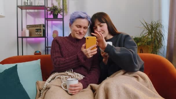 Dos Jóvenes Alegres Lesbianas Amigos Sostienen Sus Teléfonos Inteligentes Mientras — Vídeos de Stock