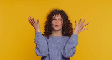 Aman Tanrım, vay canına. Heyecanlı kazanan kadın şaşkınlıkla el kaldırıyor. Büyük gözleriyle kameraya bakıyor. Ani zaferden şok oluyor. Samimi kıvırcık saçlı kız sarı stüdyo arka planında izole edilmiş.