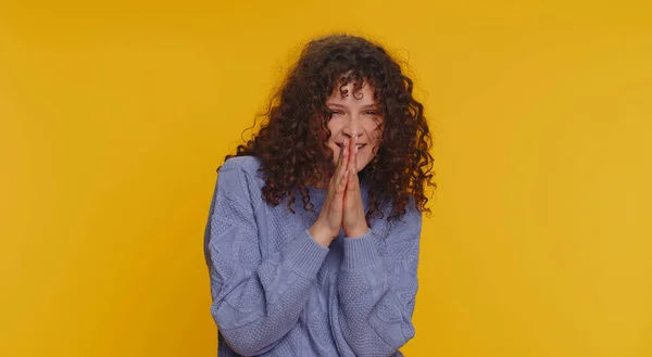 Sneaky cunning curly haired woman with tricky face gesticulating and scheming evil plan, thinking over devious villain idea, cheats, revenge, jokes, pranks. Girl isolated on yellow studio background