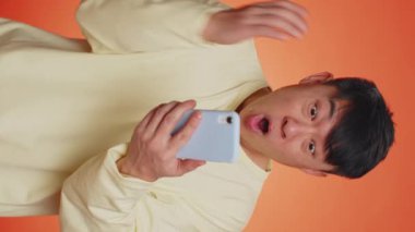 Happy excited joyful asian man use smartphone typing browsing shouting say wow yes found out great big win, good news, lottery goal achievemen, celebrating success, winning game. Vertical video shot