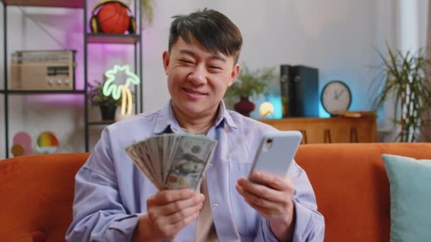 Családi Költségvetés Tervezése Mosolygó Ázsiai Férfi Számolja Pénzt Készpénzt Okostelefonnal — Stock videók