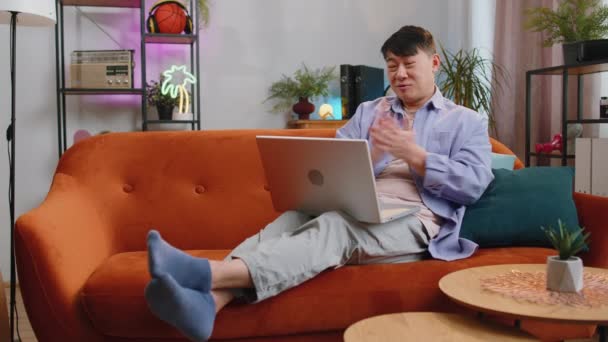Asyalı Bir Adam Kanepeye Oturmuş Kameraya Bakıyor Arkadaşlarıyla Ailesiyle Görüntülü — Stok video