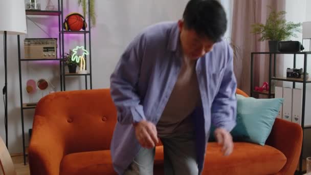 疲れたアジアのハンサムな男はリビングルームでホームソファでリラックスしてお楽しみください 幸せな中国の男は彼の目を閉じて 彼の頭の後ろに手を置く ストレスフリー — ストック動画