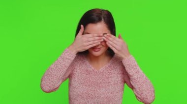 Nosy curious young woman closing eyes with hand and spying through fingers, hiding and peeping, binocular gesture, exploring way, seeking something in distance. Girl isolated on chroma key background