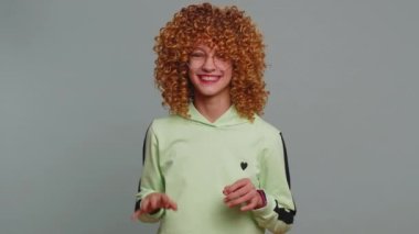 Kıvırcık saçlı, kaplan kılığına girmiş komik öfkeli genç kız, aslan taklidi yapıyor, bağırıyor, kedileri tırmalıyor, flört ediyor. Gri arka planda çocuk