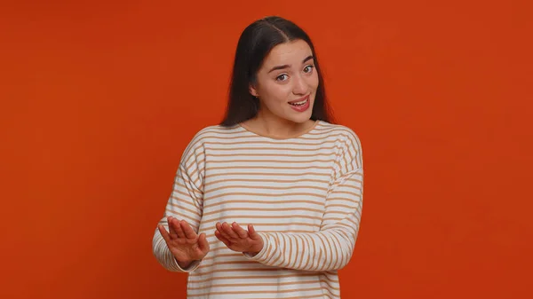 Hey you, be careful. Young woman warning with admonishing finger gesture, saying no, be careful, scolding and giving advice to avoid danger, disapproval sign. Girl isolated on red studio background