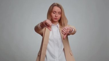 Dislike. Upset unhappy office woman in suit showing thumbs down sign gesture, expressing discontent, disapproval, dissatisfied, dislike. Business adult girl. Indoor studio shot on gray background