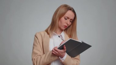 Düşünceli gazeteci genç iş kadını notlar alıyor, not defterine kalemle düşünceler yazıyor, liste yapmak için, iyi fikir. Resmi takım elbiseli bir kadın. Gri arka planda izole kadın