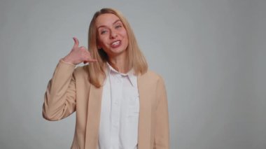 Call us, here is contact number. Business woman in formal suit looking at camera doing phone gesture like says hey you call me back, conversation. Secretary girl isolated on gray background, indoors