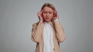 Business woman in formal office suit rubbing temples to cure headache problem, suffering from tension, migaine, stress, grimacing in pain, high blood pressure isolated alone on gray wall background
