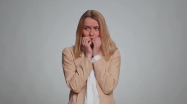 Upset scared frightened businesswoman biting nails, feeling worried nervous about serious troubles, stress and anxiety disorder, panic attack, guilty. Female girl in suit. Woman on gray background