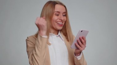 Mutlu, mutlu, neşeli, resmi takım elbiseli bir iş kadını akıllı telefon daktilo kullanıyor ve bağırarak evet diyor. Büyük kazanç, iyi haber, piyango hedefleri, başarıyı kutluyor, oyunu kazanıyor.