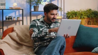 Oh my God Wow. Surprised indian man using laptop computer, receive good news message, shocked by sudden victory, celebrate lottery jackpot win purchases online shopping at home. Lifestyle technologies