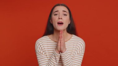 Lütfen Tanrım, beni affet. Genç kadın içtenlikle Tanrı 'ya dua ediyor ve yalvaran bir ifadeyle yukarı bakıyor, özür diliyor, umut dolu bir yüzle yalvarıyor. Milenyum kızı kırmızı stüdyo arka planında izole edilmiş.