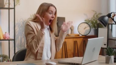 Young businesswoman fingers crossed working on laptop at home office workplace typing browsing say Wow yes found out great big lottery jackpot win, good job news, celebrating. Manager freelancer woman