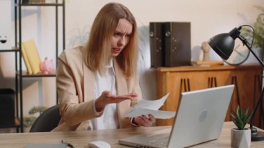 Ödenmemiş banka borçlarına bakan, evrak işleri yapan, bütçe planlayan, ofisteki ipotek ödemelerini hesaplayan stresli genç iş kadını. Serbest çalışan hoşnutsuz kadın kağıt para fırlatıyor.