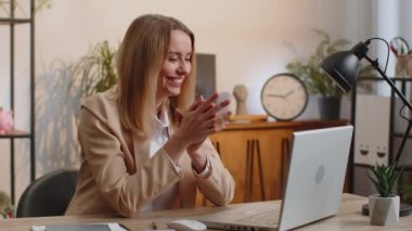 Sneaky cunning blonde young businesswoman with tricky face gesticulating and scheming evil plan, thinking over devious villain idea, cunning cheats, jokes and pranks at office workplace with laptop