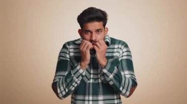 Stressed depressed indian man terrified about danger problems, suffering phobia, anxiety disorder, expresses fear, waving no, insecure, stress, panic. Hindu guy isolated on beige studio background