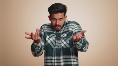 No idea, I dont know answer. Puzzled clueless uncertain indian handsome man raising hands in helpless gesture, embarrassed confused by difficult question. Confused one guy on beige studio background