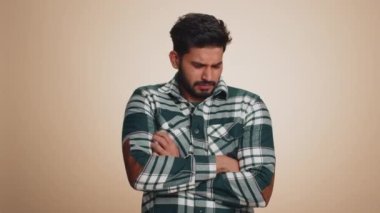 Offended sad nervous indian man having misunderstanding, frustrated after quarrel, fail, lose, ignores and does not want to communicate, talk. Guy isolated on beige studio background. People lifestyle