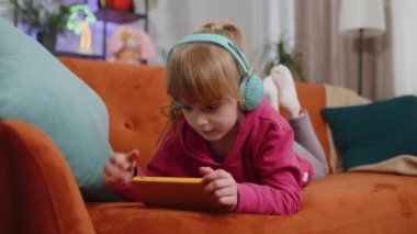 Komik kız çocuğu endişeli heyecanlı bir şekilde online yarış oynuyor ya da akıllı telefondan video oyunu oynuyor. Genç bir kız, akıllı telefon uygulaması kullanıyor. Kanepeye uzanmış, simülatörlü.