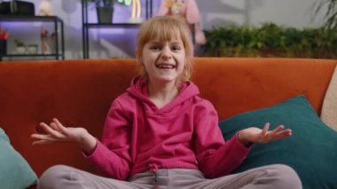 What. Why. Young child kid girl raising hands in indignant expression, asking reason of failure, demonstrating disbelief irritation by troubles. Female teen toddler at home in living room sits on sofa