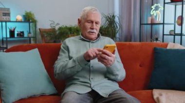 Üzücü büyükbaba, akıllı telefon daktilo kullanıyor. Ani piyango sonuçlarını kaybediyor. Kötü haber, servet kaybı, son teslim tarihi, virüs. Oturma odasındaki kanepede oturan yaşlı adam.