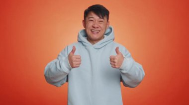 Gibi. Kapüşonlu Çinli Asyalı bir adam bir şeyi onaylıyor ya da olumlu cevap veriyor. Reklamlar iyi şeyleri sever. Yakışıklı Japon adam turuncu stüdyoda tek başına izole edilmiş.