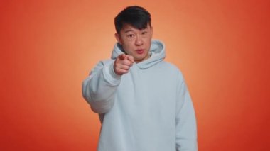 Seni seçiyorum. Asyalı adam kamerayı gösterip neşeli bir ifadeyle bakıyor, seçim yapıyor, yön gösteriyor. Yakışıklı gülümseyen Çinli adam turuncu stüdyo arka planında tek başına.