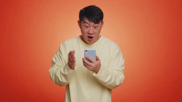 Щасливий Радісний Азіатський Чоловік Жовтому Светрі Використовує Смартфон Вводячи Обіг — стокове відео