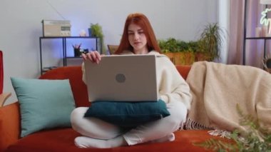 Serbest çalışan kadın dizüstü bilgisayarı açıyor, not defteriyle eğitime başlıyor, mesajlar gönderiyor, online alışverişler yapıyor, evdeki oturma odasında film izliyor. Kanepede oturan kızıl saçlı kız. Yaşam biçimi