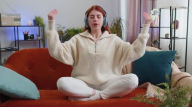 Sakin ol, rahatla, iç denge. Kızıl saçlı kadın derin derin nefes alıyor, gözleri kapalı, konsantre düşüncelerle meditasyon yapıyor, evinde huzurlu bir zihin. Kanepede oturan kız