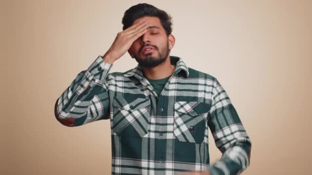 一位英俊的印度大胡子男子穿着衬衫擦拭太阳穴以治疗头痛问题 他患有紧张 高血压等症状 这些症状都是在米色墙的背景下孤立出来的 — 图库视频影像
