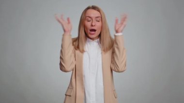 Heyecanlı iş kadını kafasına dokunuyor ve patlama gösteriyor endişeli ve şok olmuş görünüyor, başarı fikrini kutluyor. Kazandığına şaşıran bir kız. Gri stüdyo arka planında tek başına.