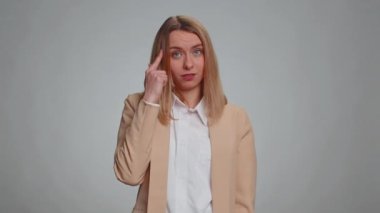 Sen delisin, aklın yerinde değil. İş kadını portresi kamerayı işaret ediyor ve aptalca bir jest yapıyor, bir aptalı delice plan için suçluyor. Resmi takım elbiseli bir kadın. Gri arka planda izole kadın