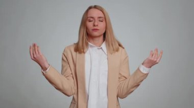 Sakin ol, rahatla, iç denge. İş kadını derin nefes alıyor Mudra jesti, gözleri kapalı, konsantre düşüncelerle meditasyon yapıyor, huzurlu bir zihin. Gri arka planda takım elbiseli kadın.